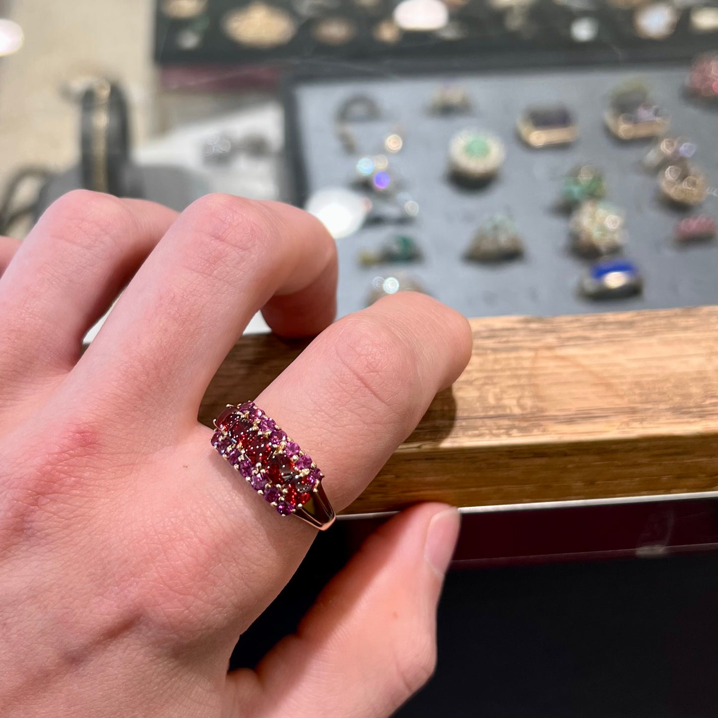 A gold ring set with buff cut cushion shaped almandine garnets with round cut purple rhodolite garnet accents.