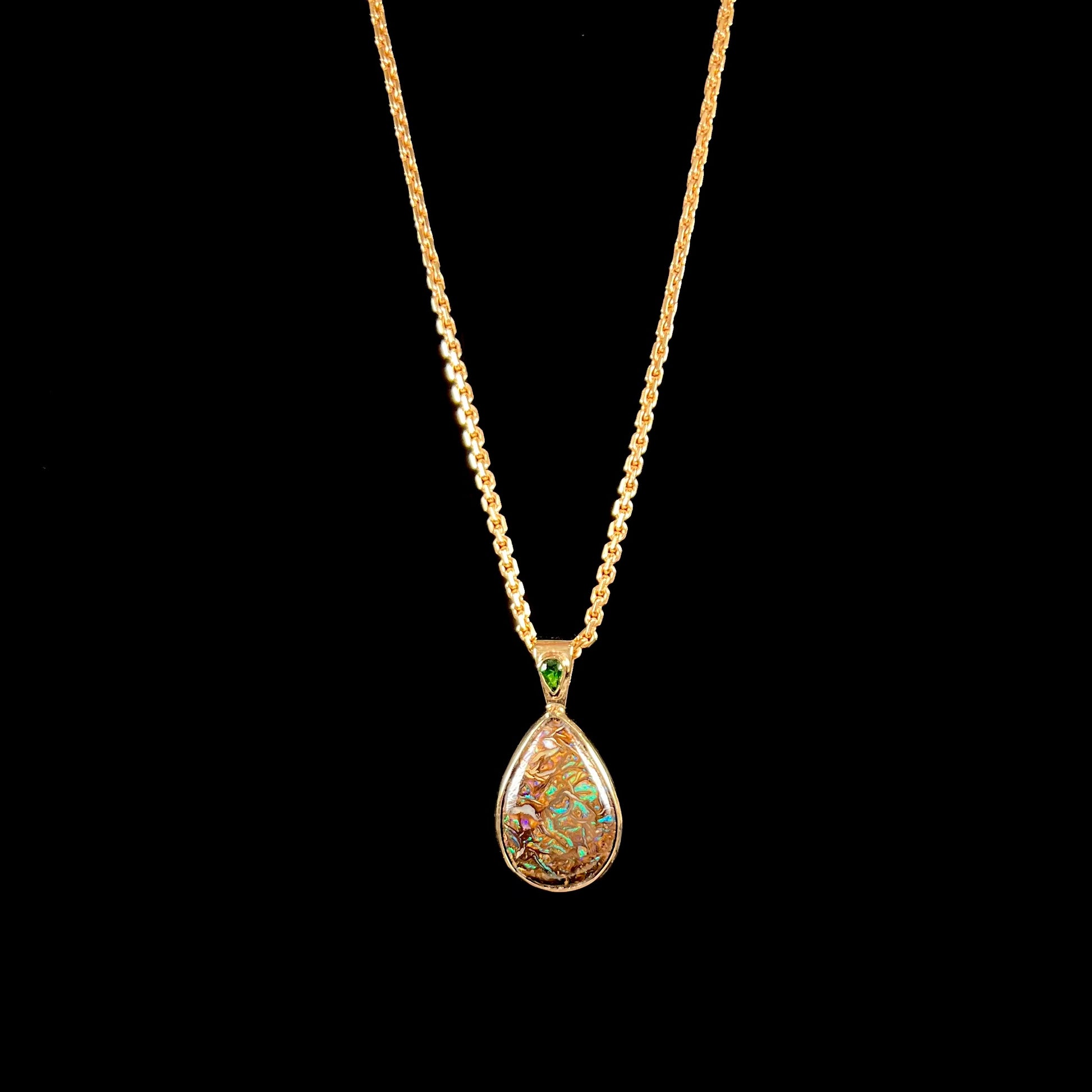 A ladies' yellow gold pendant set with a natural Koroit, Australian boulder opal and a tsavorite garnet accent stone.