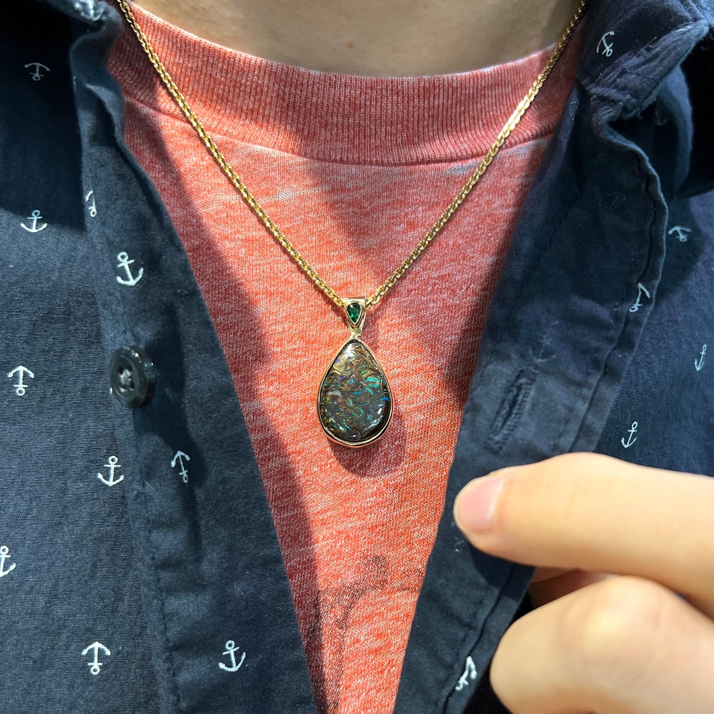 A ladies' yellow gold pendant set with a natural Koroit, Australian boulder opal and a tsavorite garnet accent stone.