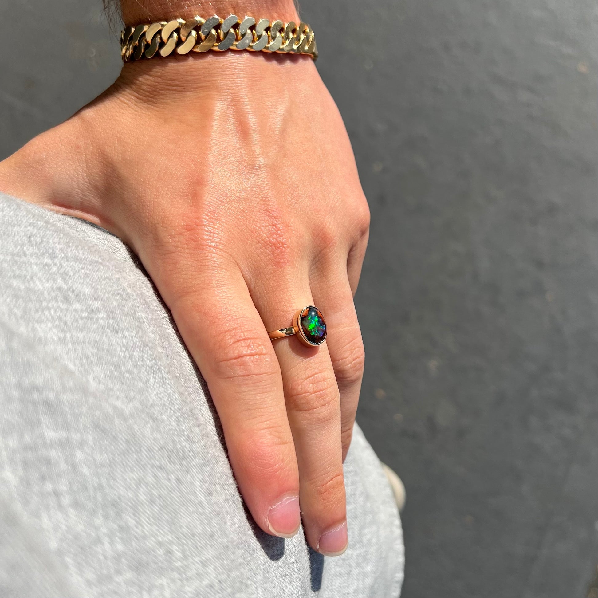 A ladies' yellow gold solitaire ring bezel set with an oval cabochon cut natural black Mexican cantera fire opal stone.