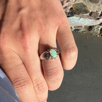 A ladies' white gold ring set with a halo of diamonds and an oval cabochon cut Australian opal.