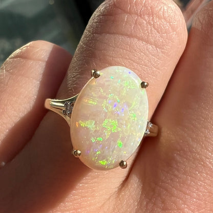A ladies' yellow gold ring set with two diamonds and an oval cut natural opal stone.