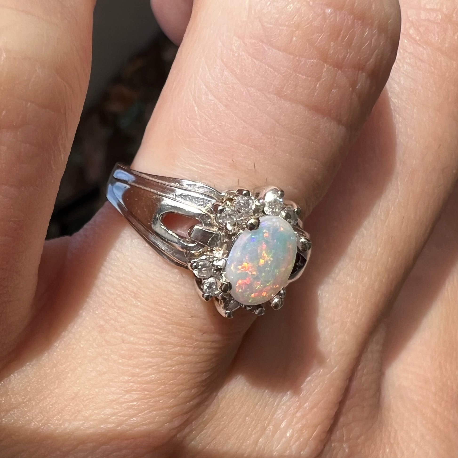 A ladies' white gold ring set with a halo of diamonds and an oval cabochon cut Australian opal.