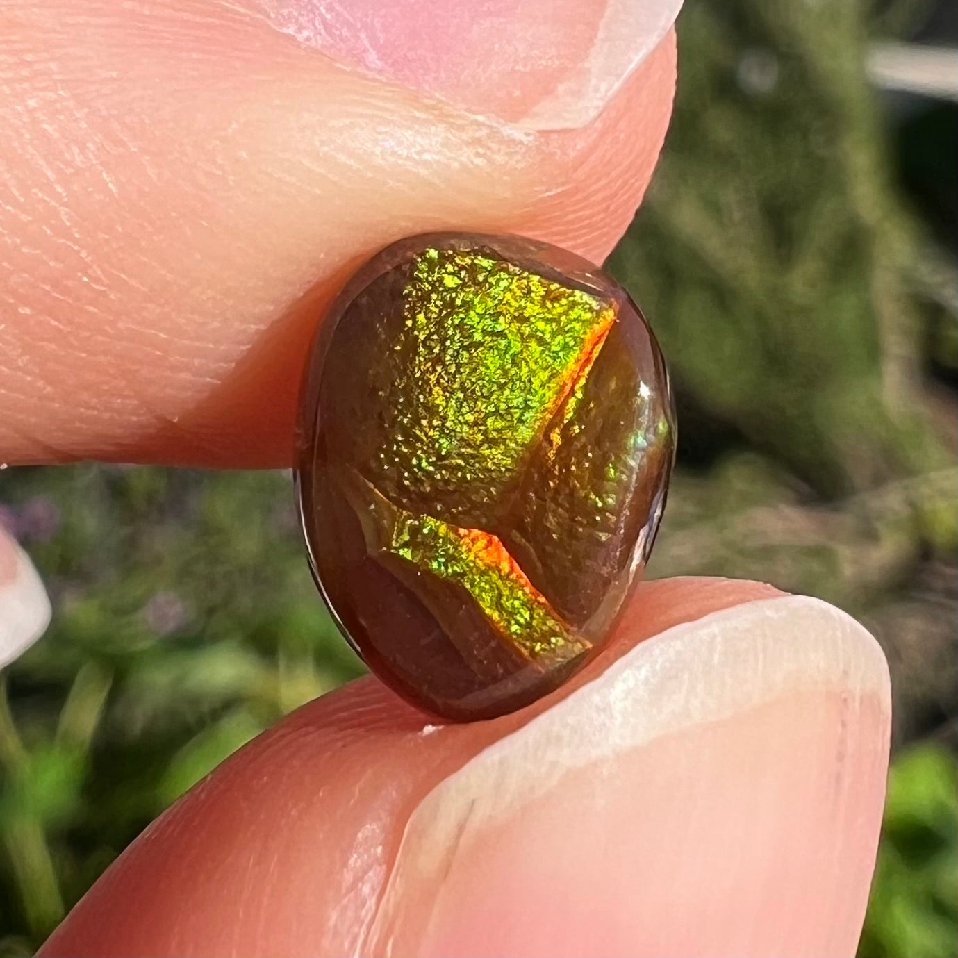 A pear shaped Mexican fire agate cabochon.  The stone has a glittery luster with green and orange colors.