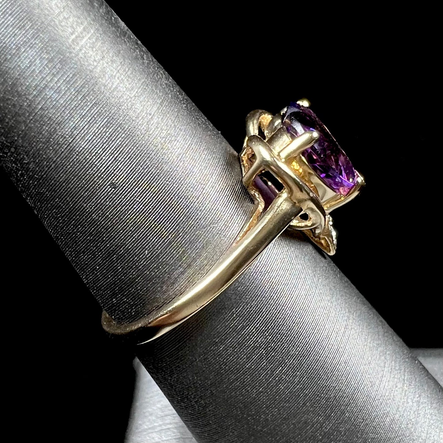 A ladies' yellow gold ring set with a heart shaped amethyst and round cut diamond accents.