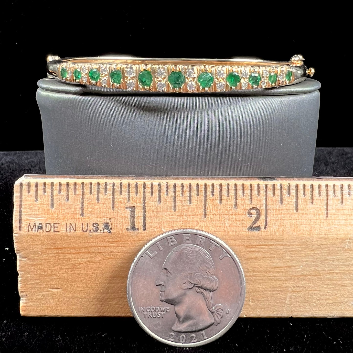 A ladies' yellow gold bangle bracelet set with round cut emeralds and diamonds.