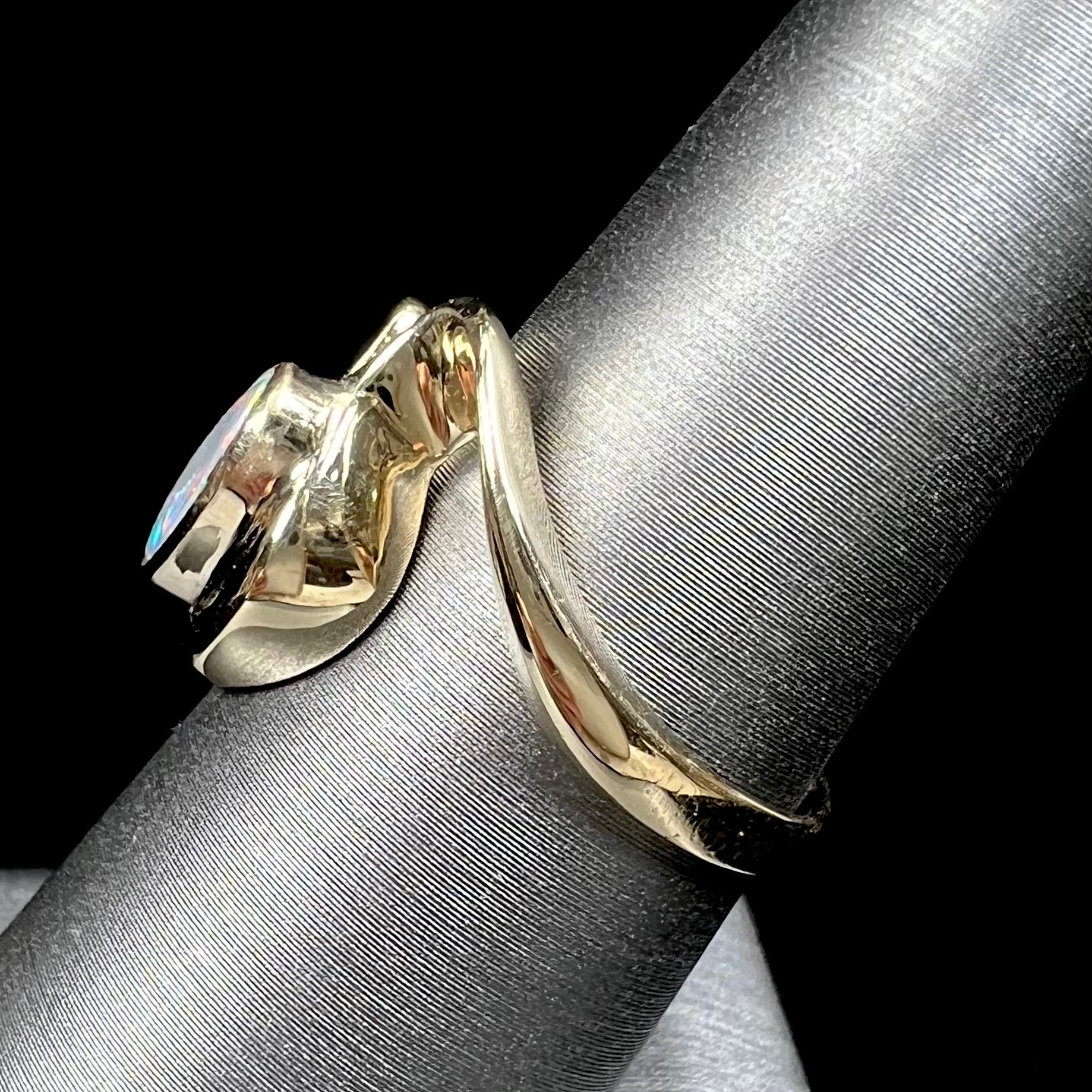 A ladies' yellow gold, bezel set ring mounted with a natural 1.15 carat black opal and round diamond.