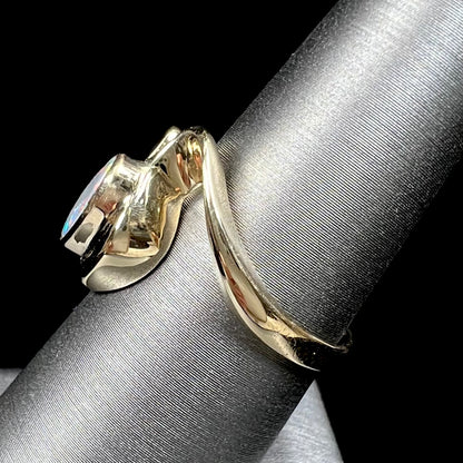 A ladies' yellow gold, bezel set ring mounted with a natural 1.15 carat black opal and round diamond.