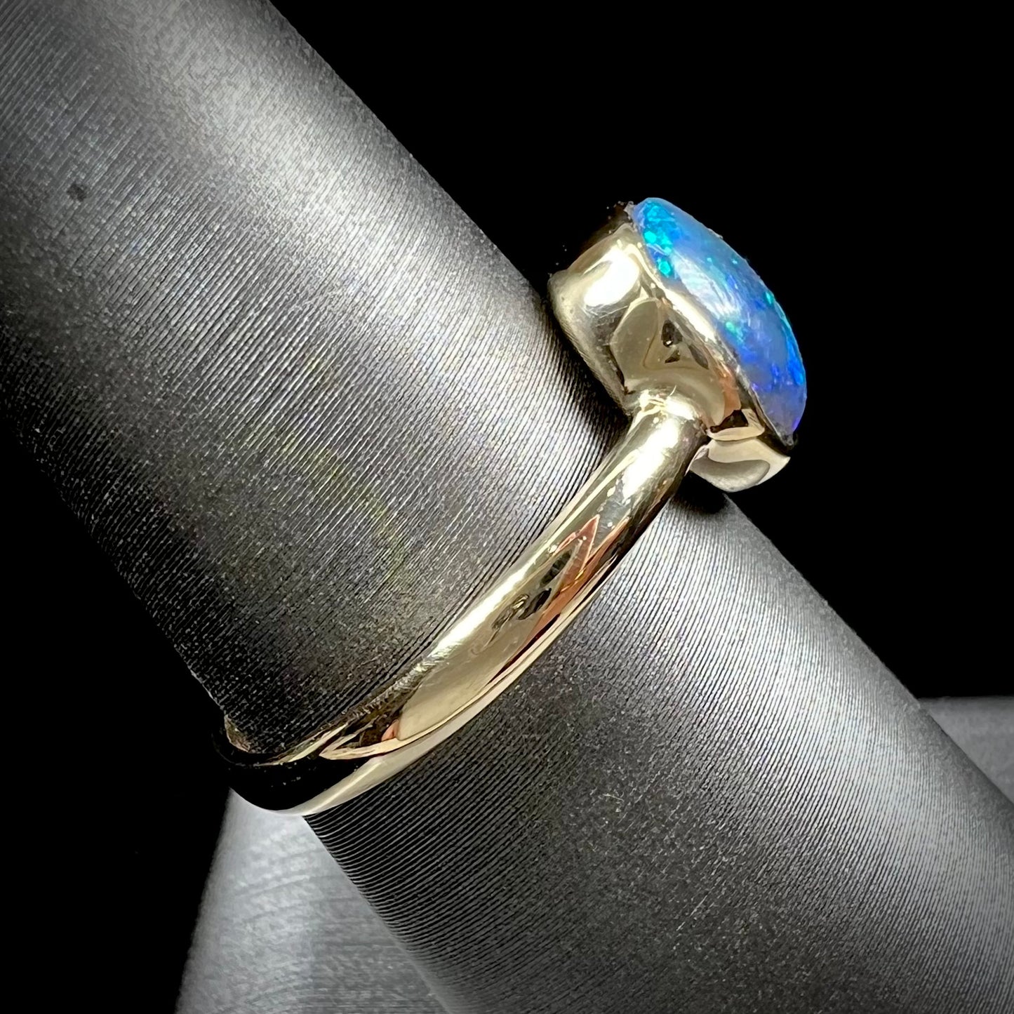 A ladies' natural black crystal opal solitaire ring handmade in 14 karat yellow gold.