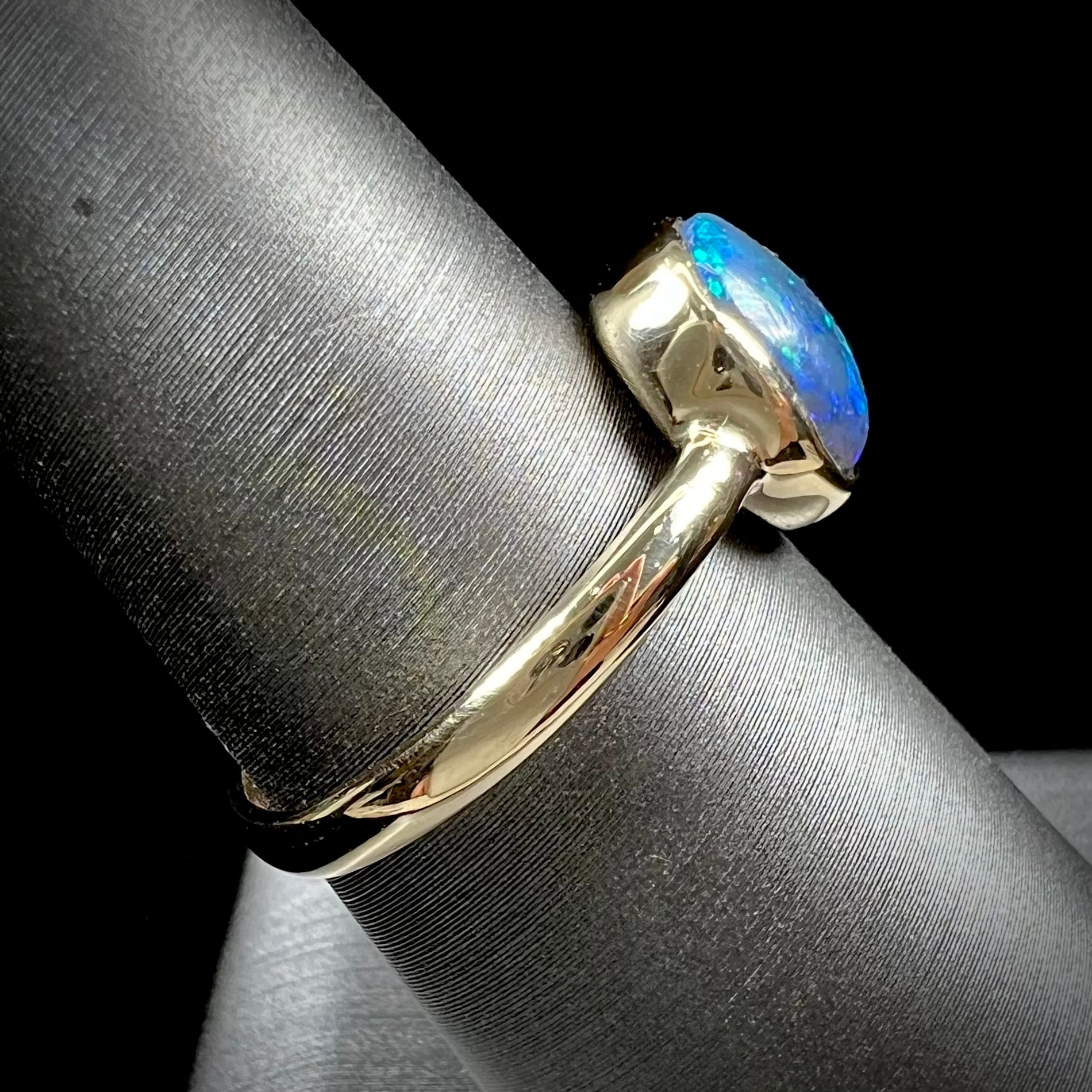 A ladies' natural black crystal opal solitaire ring handmade in 14 karat yellow gold.