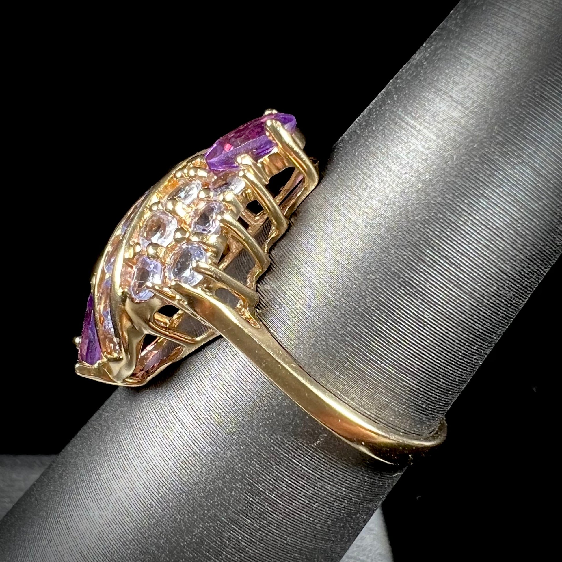 A ladies' gold ring set with a cluster of round tanzanites and two pear shaped amethyst accent stones.