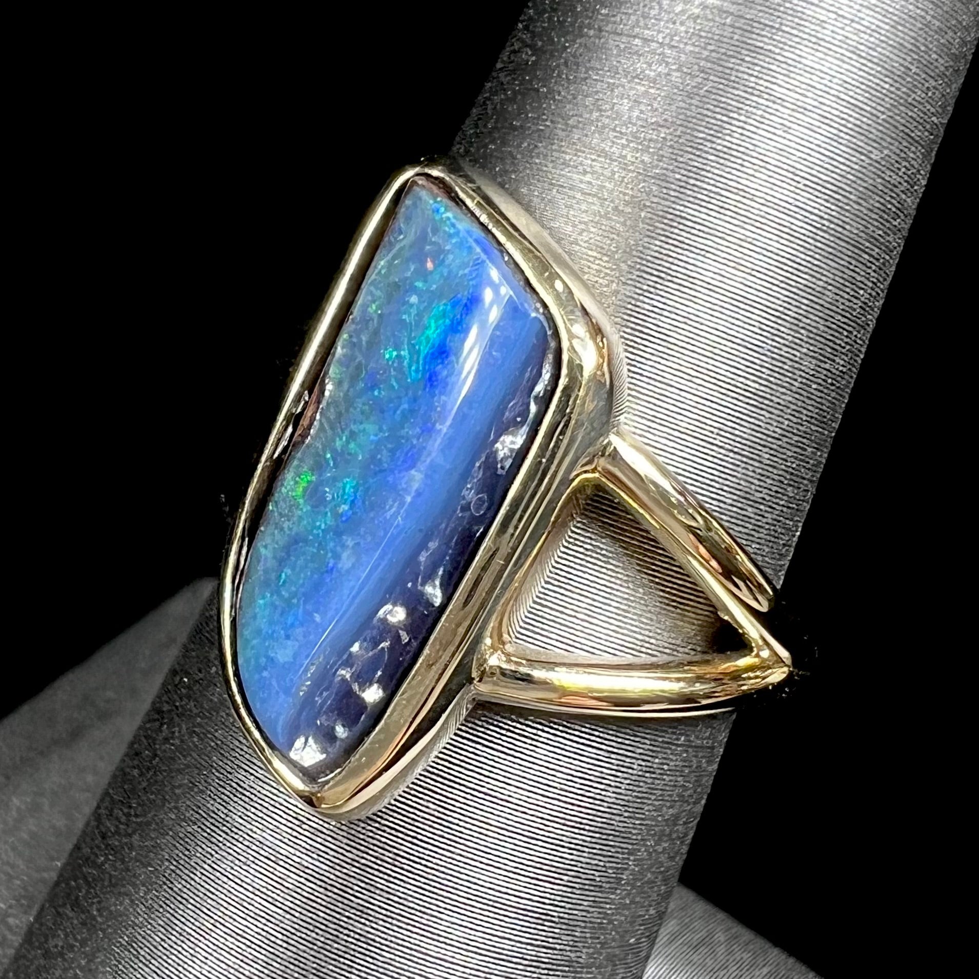 A ladies' split shank gold ring bezel set with a natural, Australian black boulder opal.