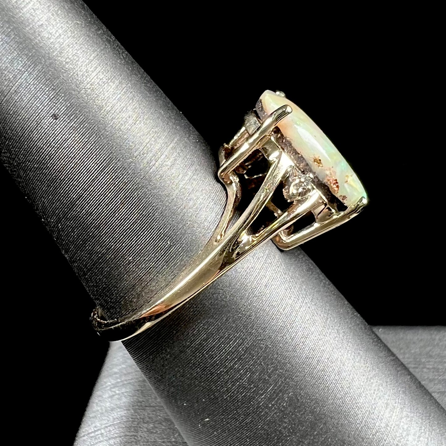 A ladies' Australian boulder opal ring set in yellow gold with diamond accents.  The opal shimmers green and pink and has fissure inclusions.