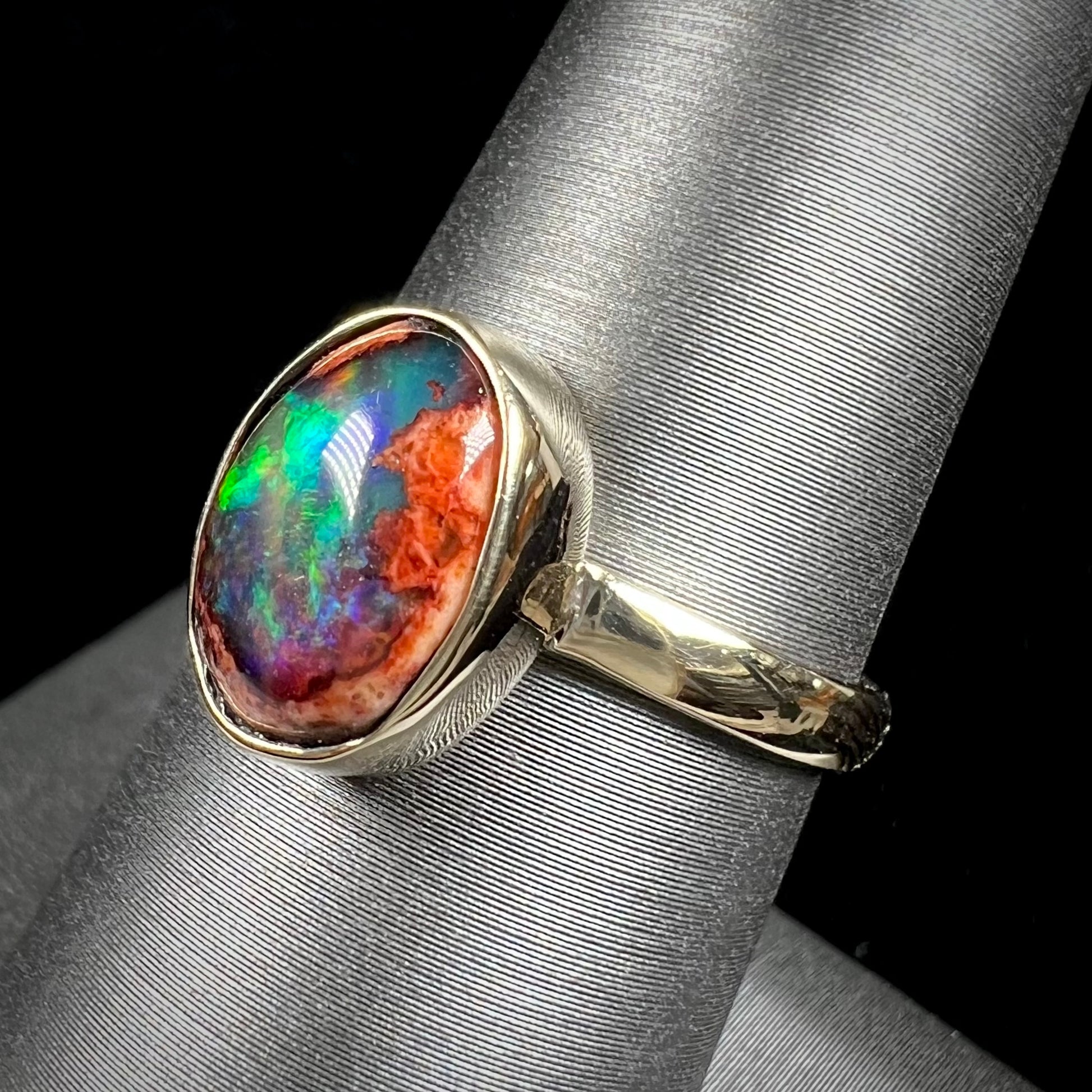 A ladies' yellow gold solitaire ring bezel set with an oval cabochon cut natural black Mexican cantera fire opal stone.
