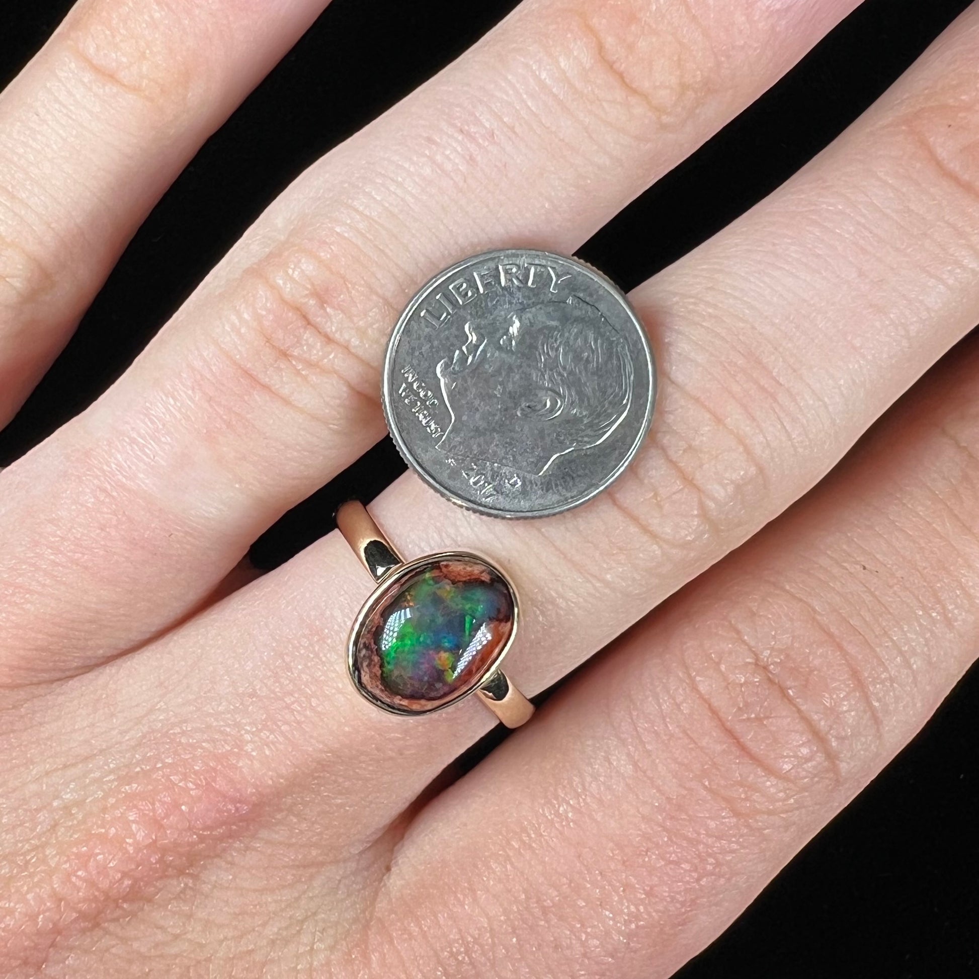 A ladies' yellow gold solitaire ring bezel set with an oval cabochon cut natural black Mexican cantera fire opal stone.