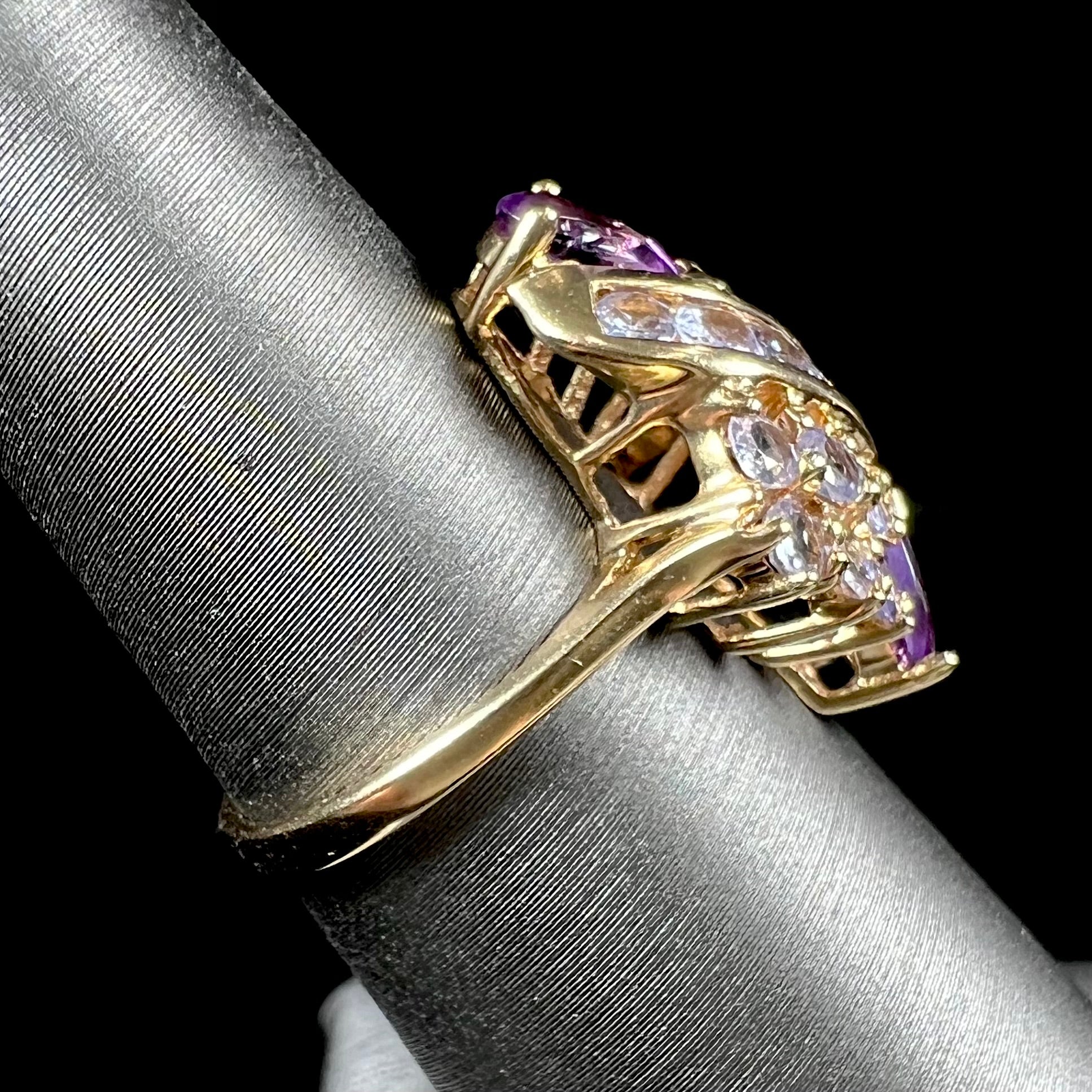 A ladies' gold ring set with a cluster of round tanzanites and two pear shaped amethyst accent stones.