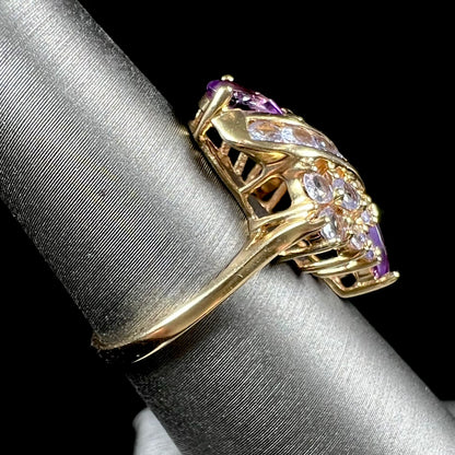 A ladies' gold ring set with a cluster of round tanzanites and two pear shaped amethyst accent stones.