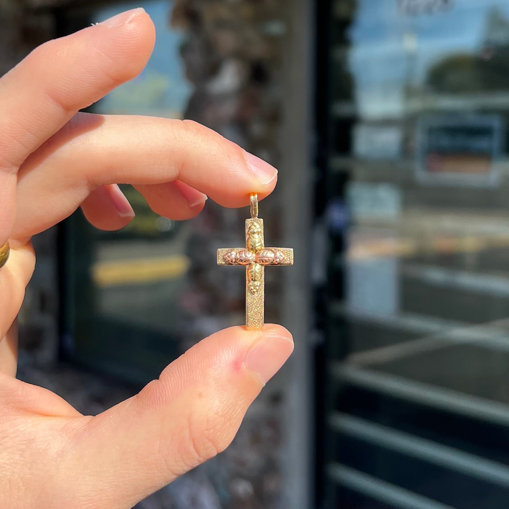 A cross made from yellow and rose gold Black Hills gold.  The cross features a leaf design.