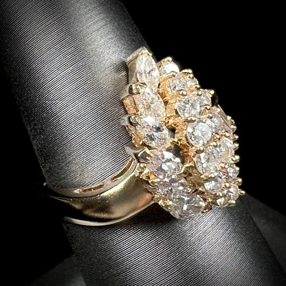 A yellow gold diamond cluster ring set with round, marquise, and baguette cut diamonds.