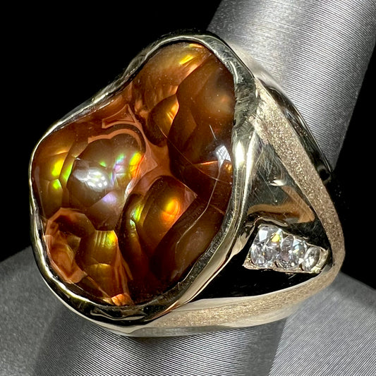 A men's heavy yellow gold ring set with a Mexican fire agate stone and three round brilliant cut diamond accents.