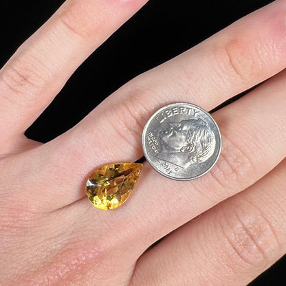A loose, pear shaped golden beryl gemstone.