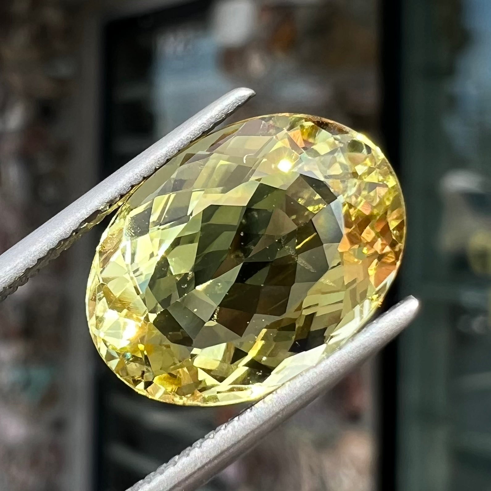 A faceted oval cut golden beryl gemstone.  The stone is a greenish light yellow.