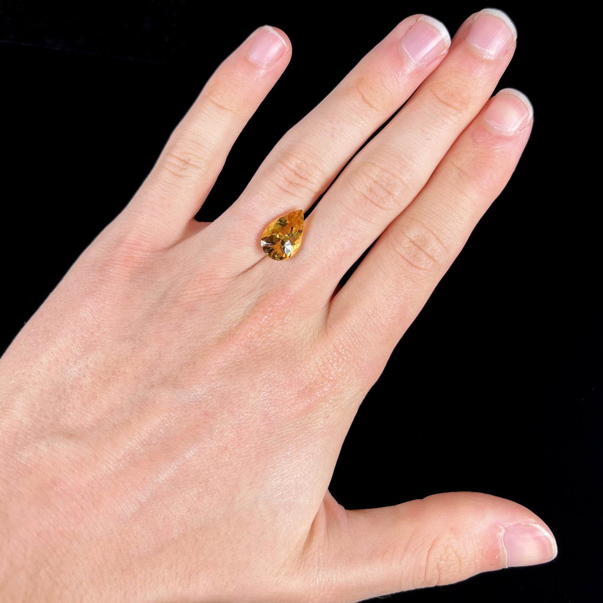 A loose, pear shaped golden beryl gemstone.