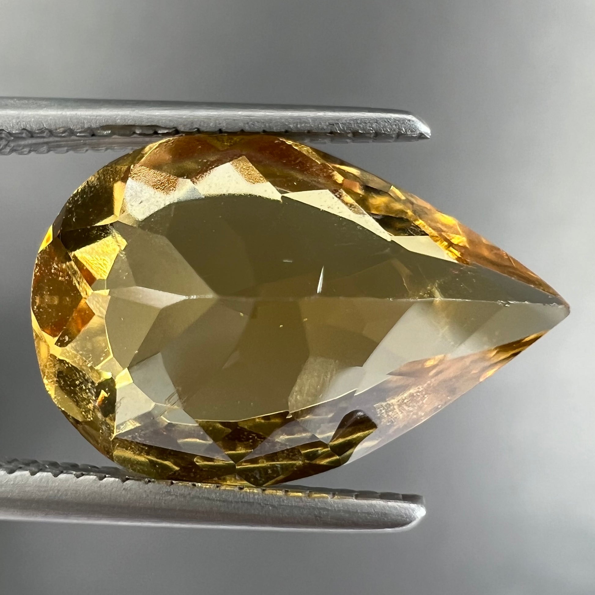 A loose, pear shaped golden beryl gemstone.
