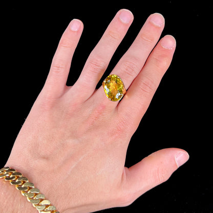 An 18 karat yellow gold solitaire cocktail ring set with a faceted oval cut golden beryl gemstone.