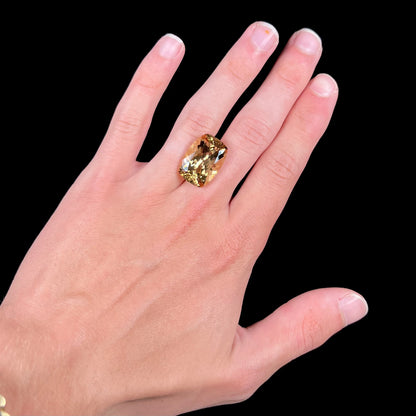 A loose, cushion cut golden beryl stone.
