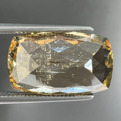 A loose, checkerboard cushion cut golden topaz gemstone.  The stone is a yellow color.
