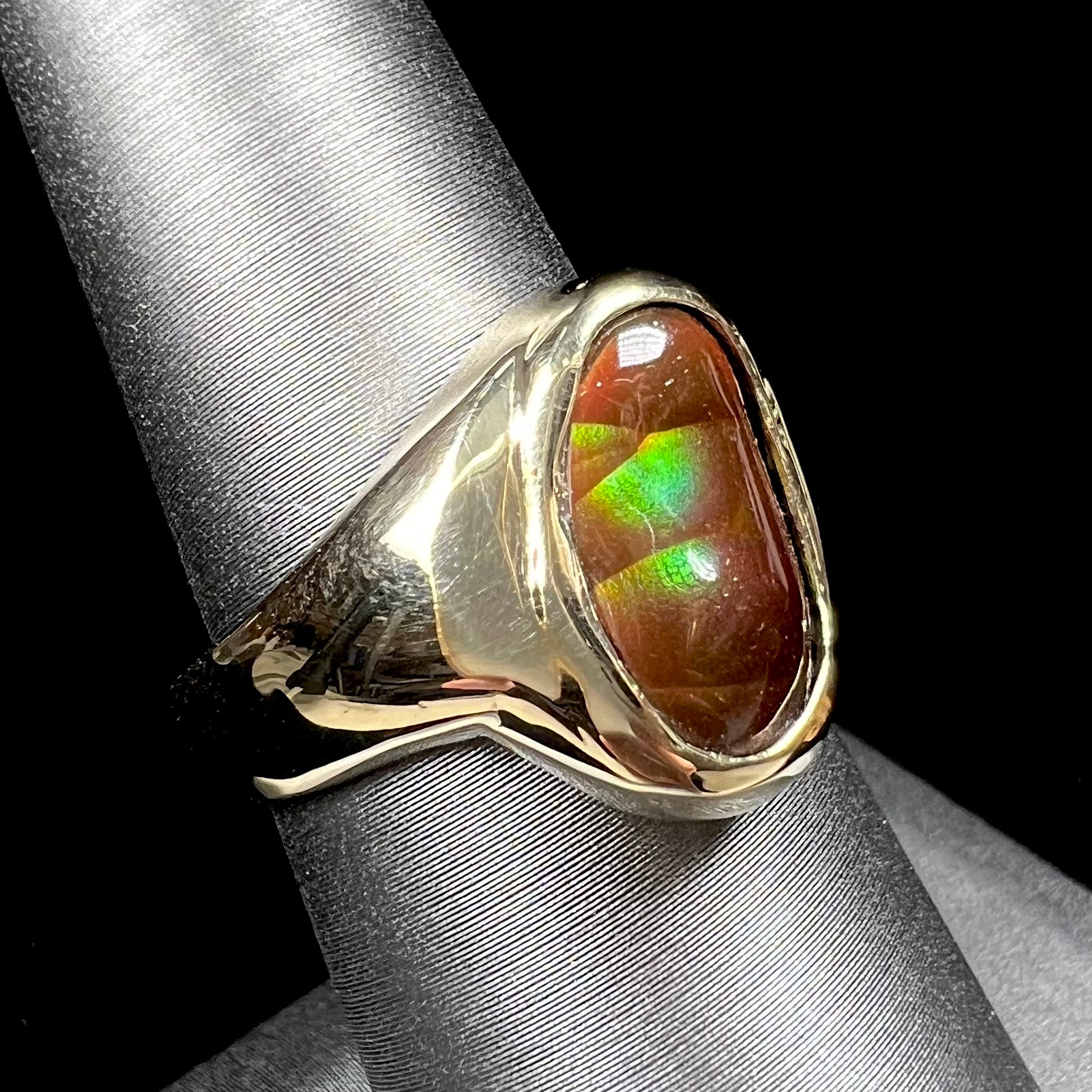 A yellow gold unisex Mexican fire agate solitaire ring.  The stone exhibits a snakeskin pattern with green, yellow, orange, and blue colors.