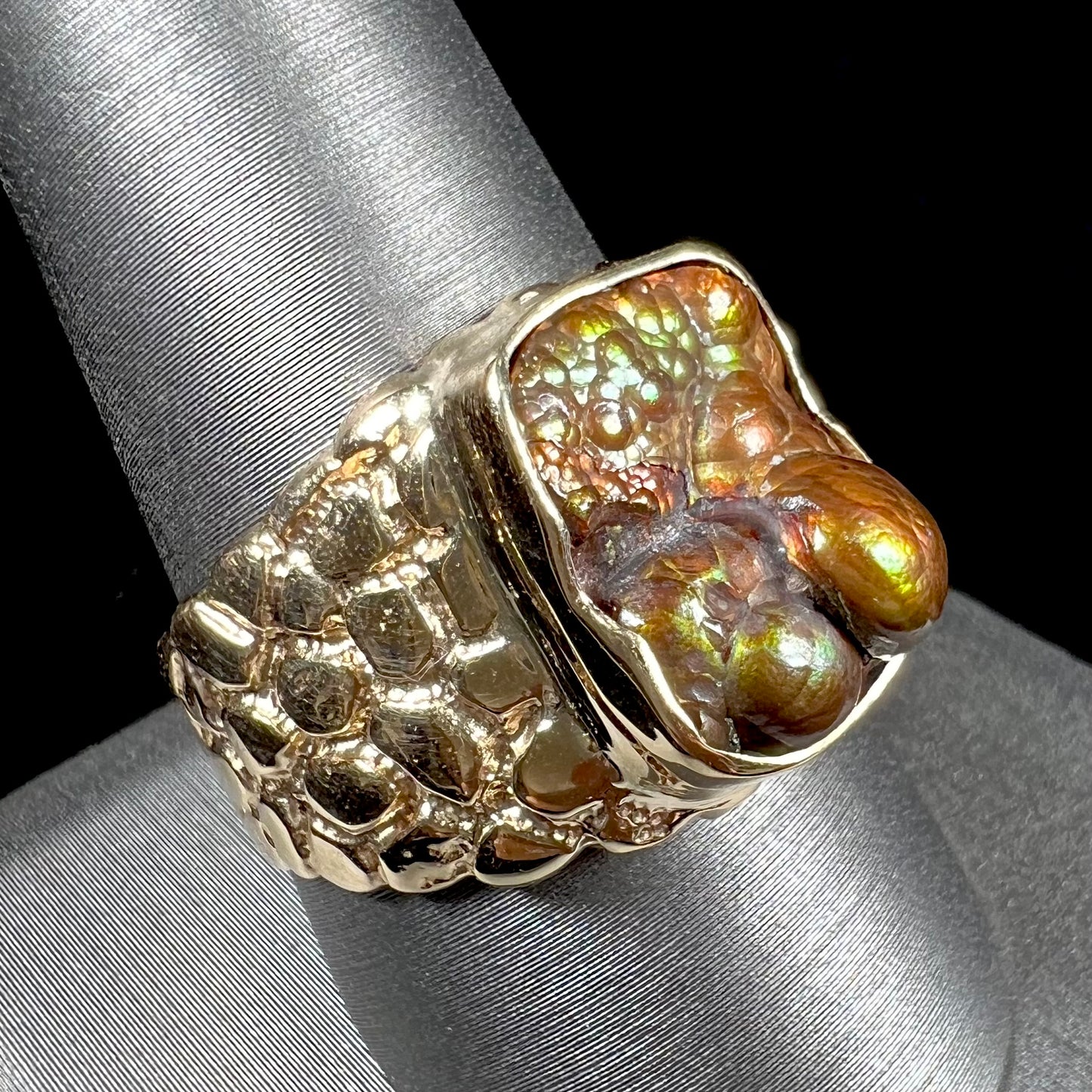 A men's yellow gold, nugget style ring set with a bubbly, California fire agate stone.