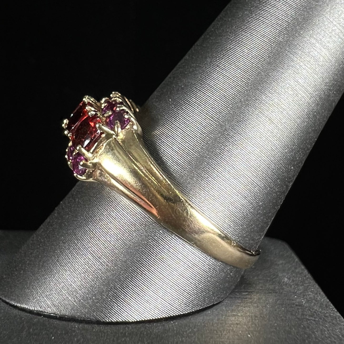 A gold ring set with buff cut cushion shaped almandine garnets with round cut purple rhodolite garnet accents.