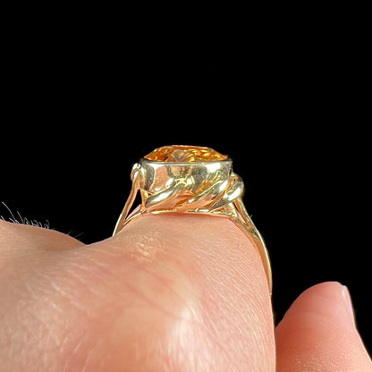 A ladies' yellow gold solitaire ring set with an 8.00 carat oval cut orange hessonite garnet.