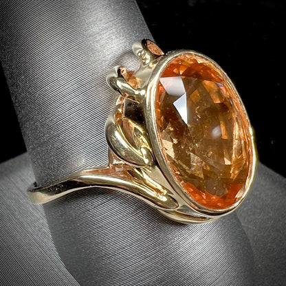 A ladies' yellow gold solitaire ring set with an 8.00 carat oval cut orange hessonite garnet.