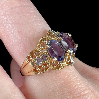 A ladies' three stone iolite ring in yellow gold set with diamond and B grade tanzanite accents.