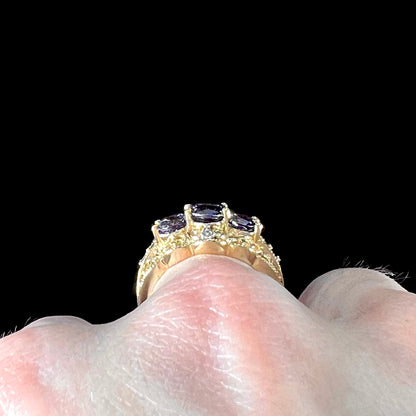 A ladies' three stone iolite ring in yellow gold set with diamond and B grade tanzanite accents.