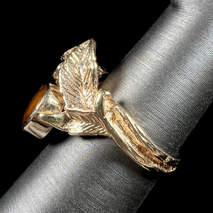 A ladies' yellow gold flower style ring set with an oval cabochon cut fire agate and diamond accents.