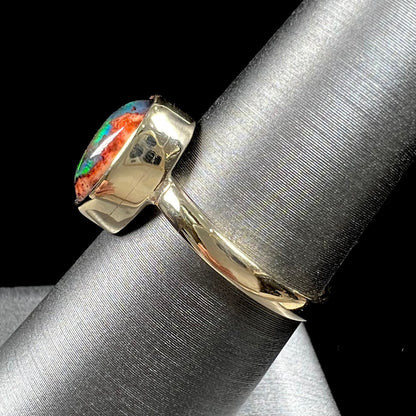 A ladies' yellow gold solitaire ring bezel set with an oval cabochon cut natural black Mexican cantera fire opal stone.