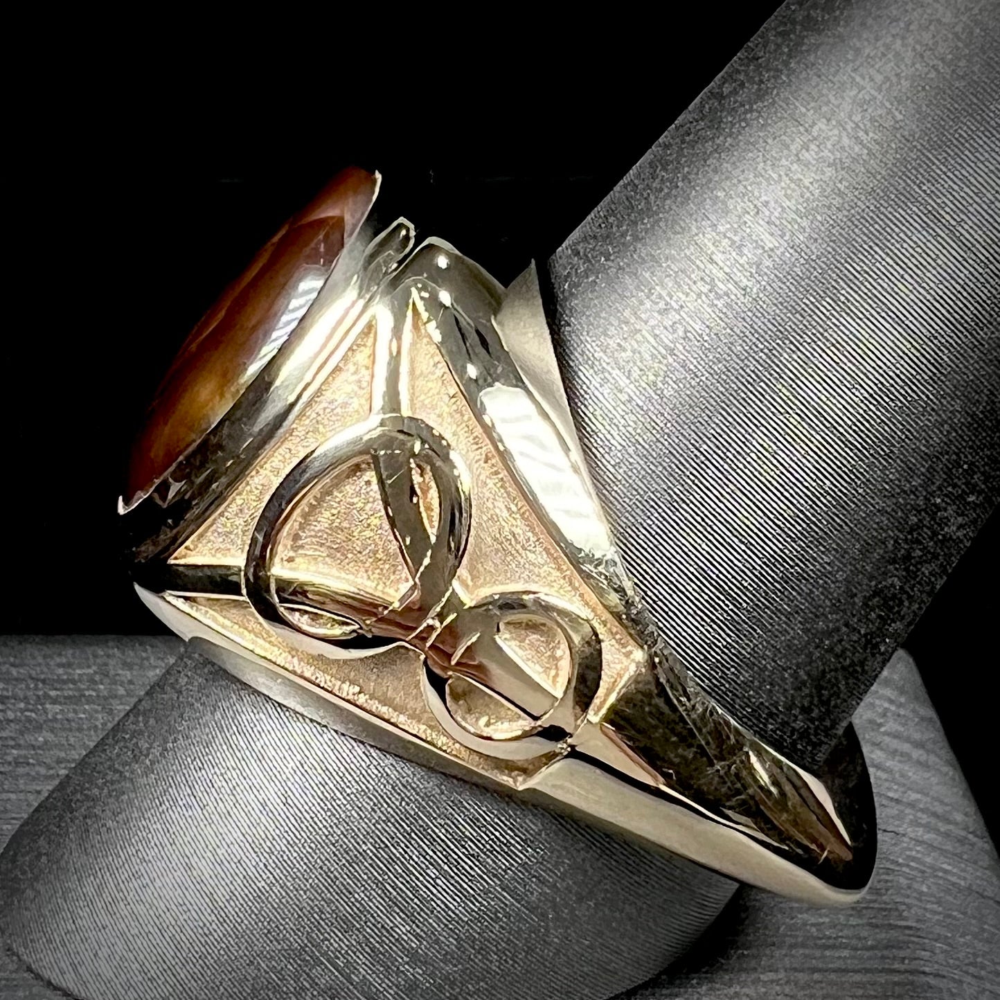 A men's solid yellow gold ring set with a Mexican fire agate stone.  The fire agate has a puple bull's eye pattern.