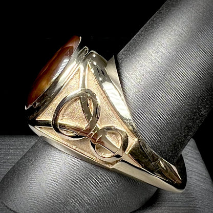 A men's solid yellow gold ring set with a Mexican fire agate stone.  The fire agate has a puple bull's eye pattern.