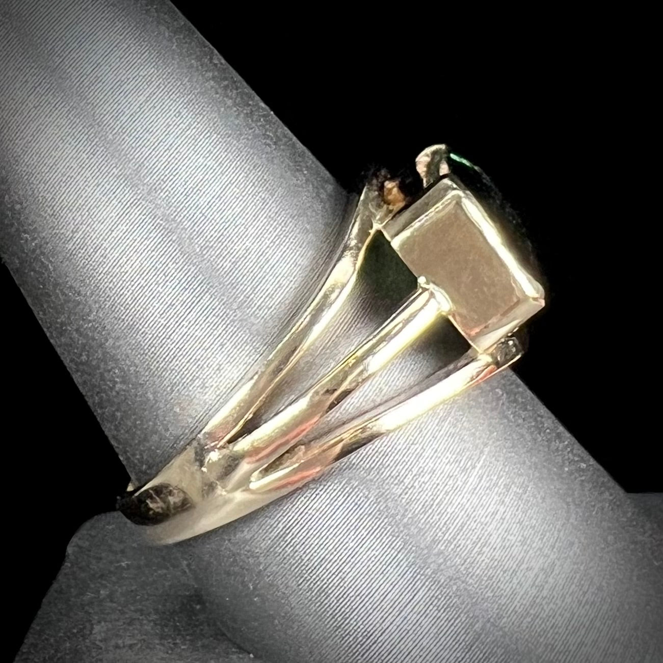 A men's emerald cut tricolor tourmaline solitaire ring in yellow gold.  The tourmaline shifts from green to blue green to blue.