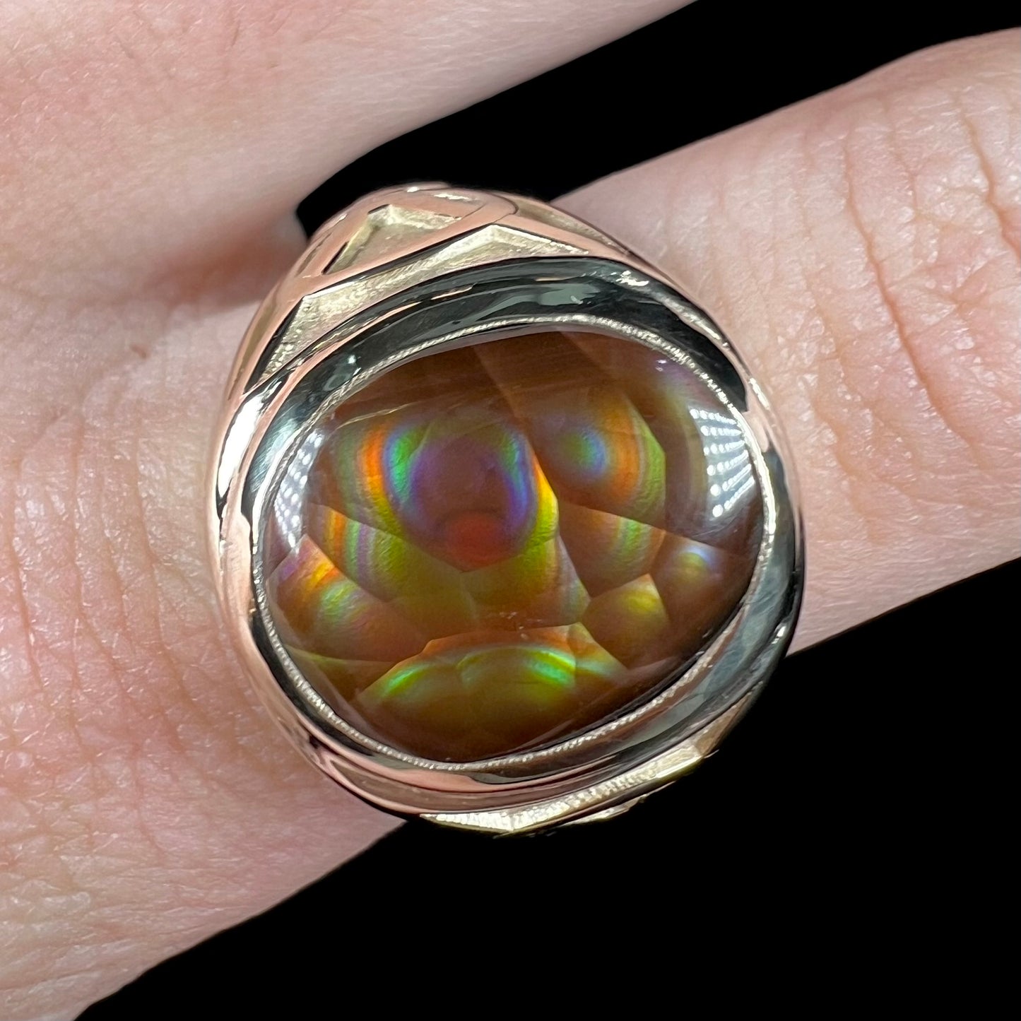 A men's solid yellow gold ring set with a Mexican fire agate stone.  The fire agate has a puple bull's eye pattern.