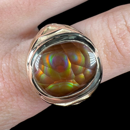 A men's solid yellow gold ring set with a Mexican fire agate stone.  The fire agate has a puple bull's eye pattern.