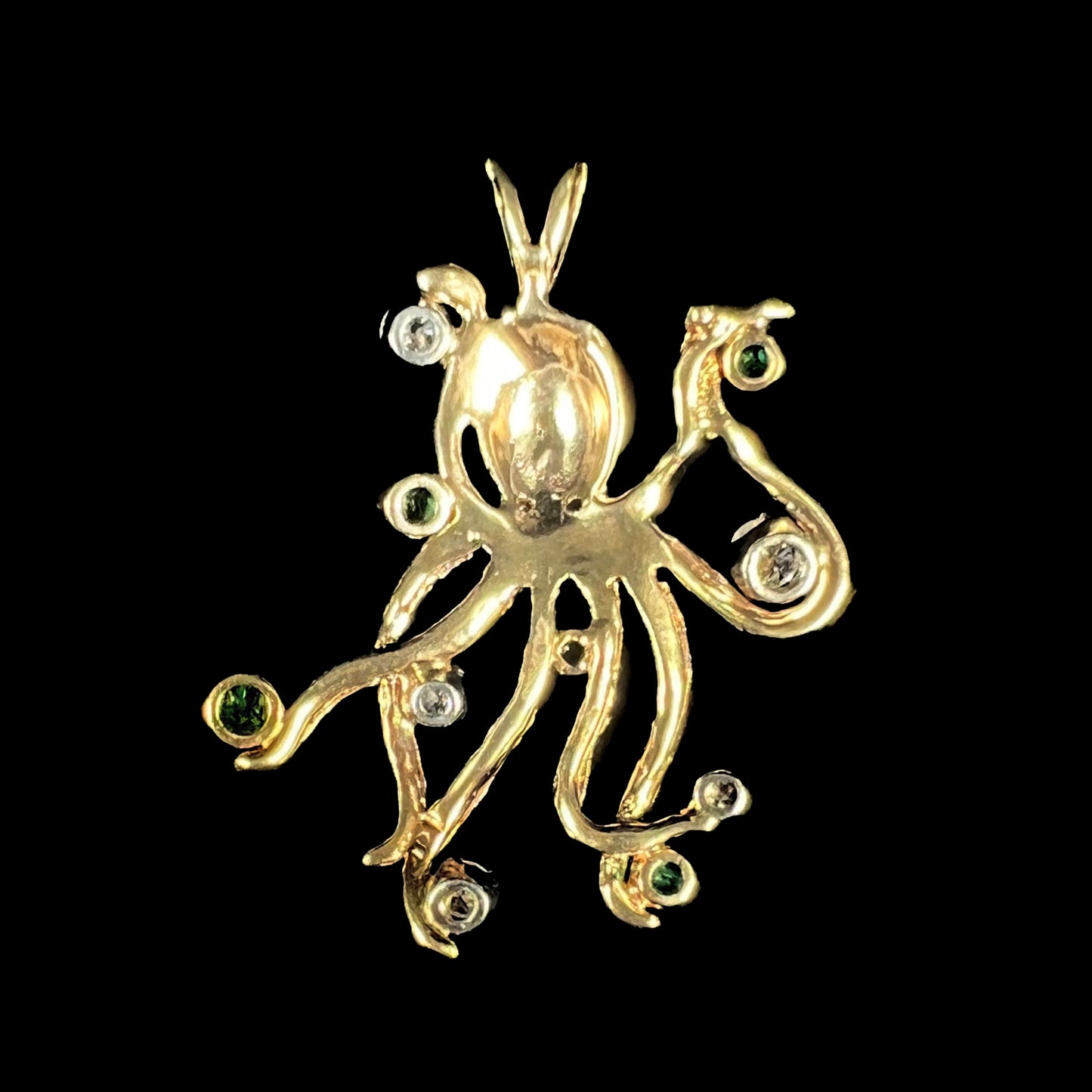 A yellow gold octopus pendant set with round cut emeralds and diamonds in the tentacles.