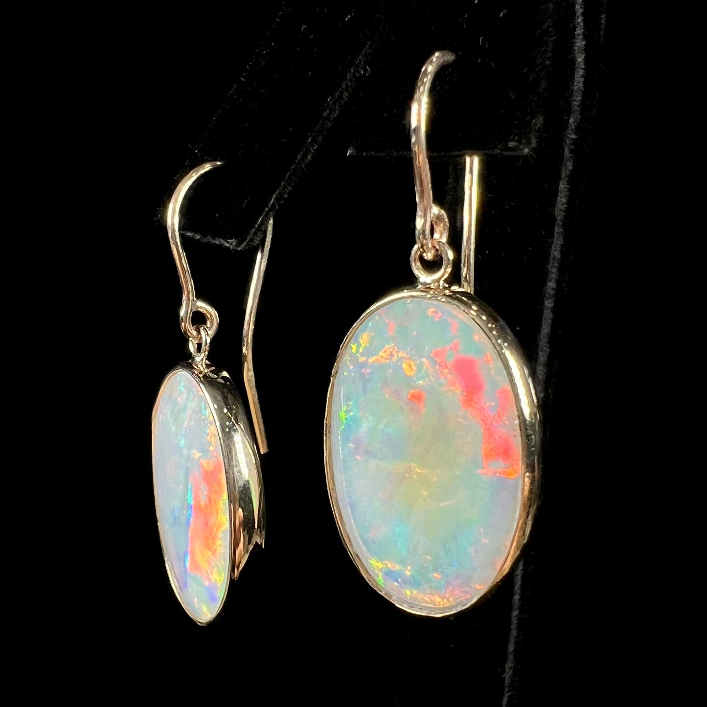 A pair of yellow gold earrings bezel set with oval cabochon cut natural opal stones.