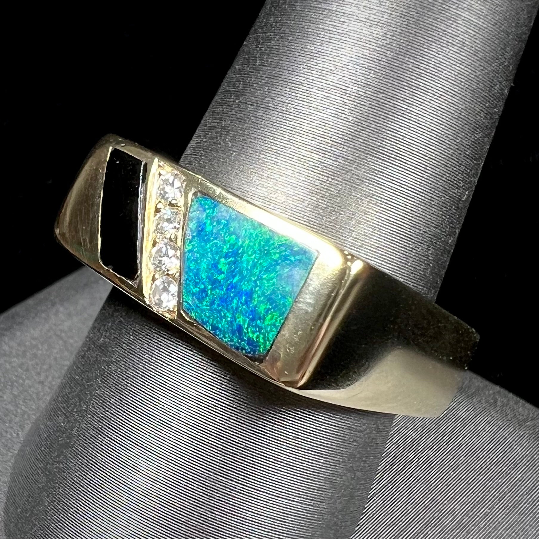 A men's yellow gold ring inlay set with onyx, natural black opal, and four diamonds.