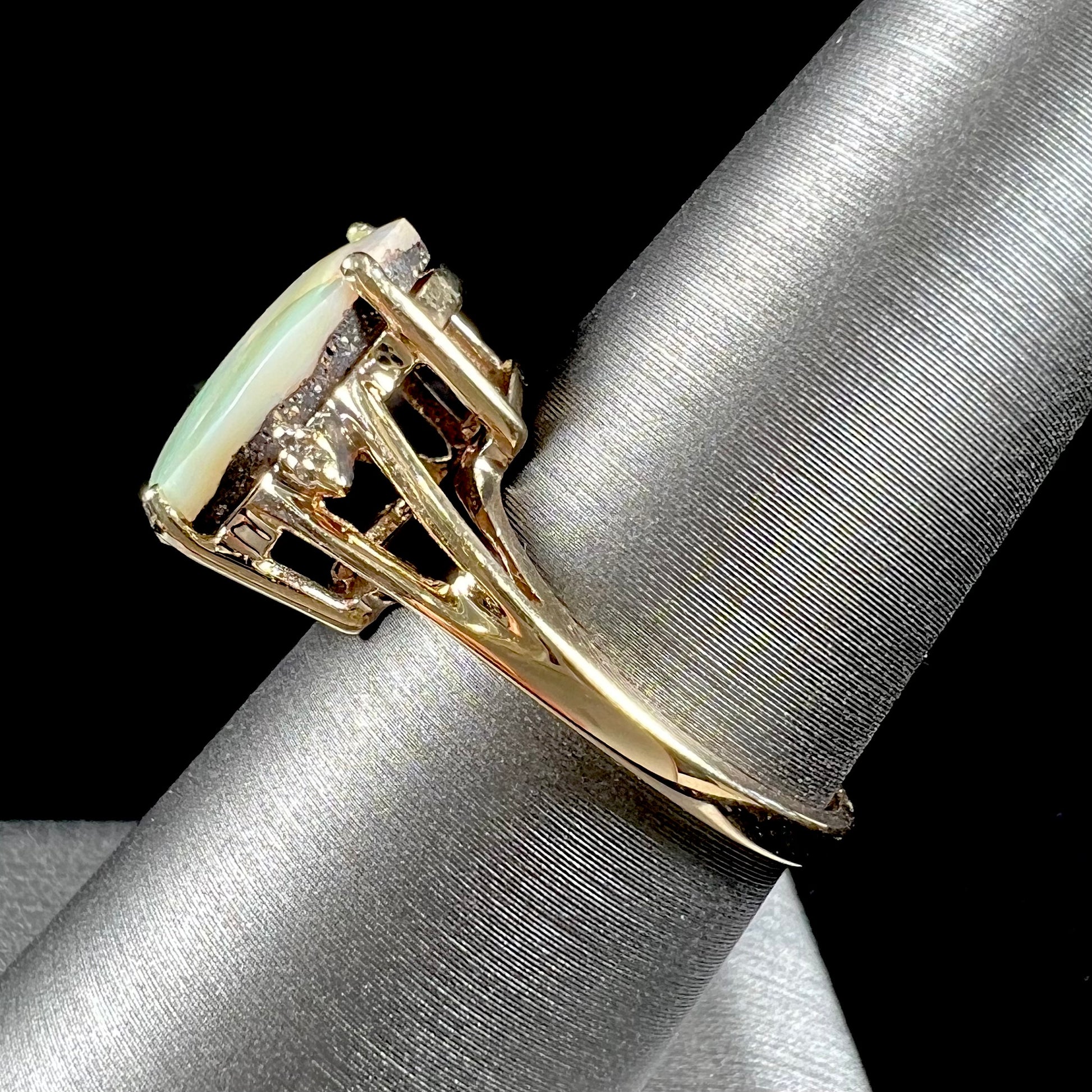 A ladies' Australian boulder opal ring set in yellow gold with diamond accents.  The opal shimmers green and pink and has fissure inclusions.