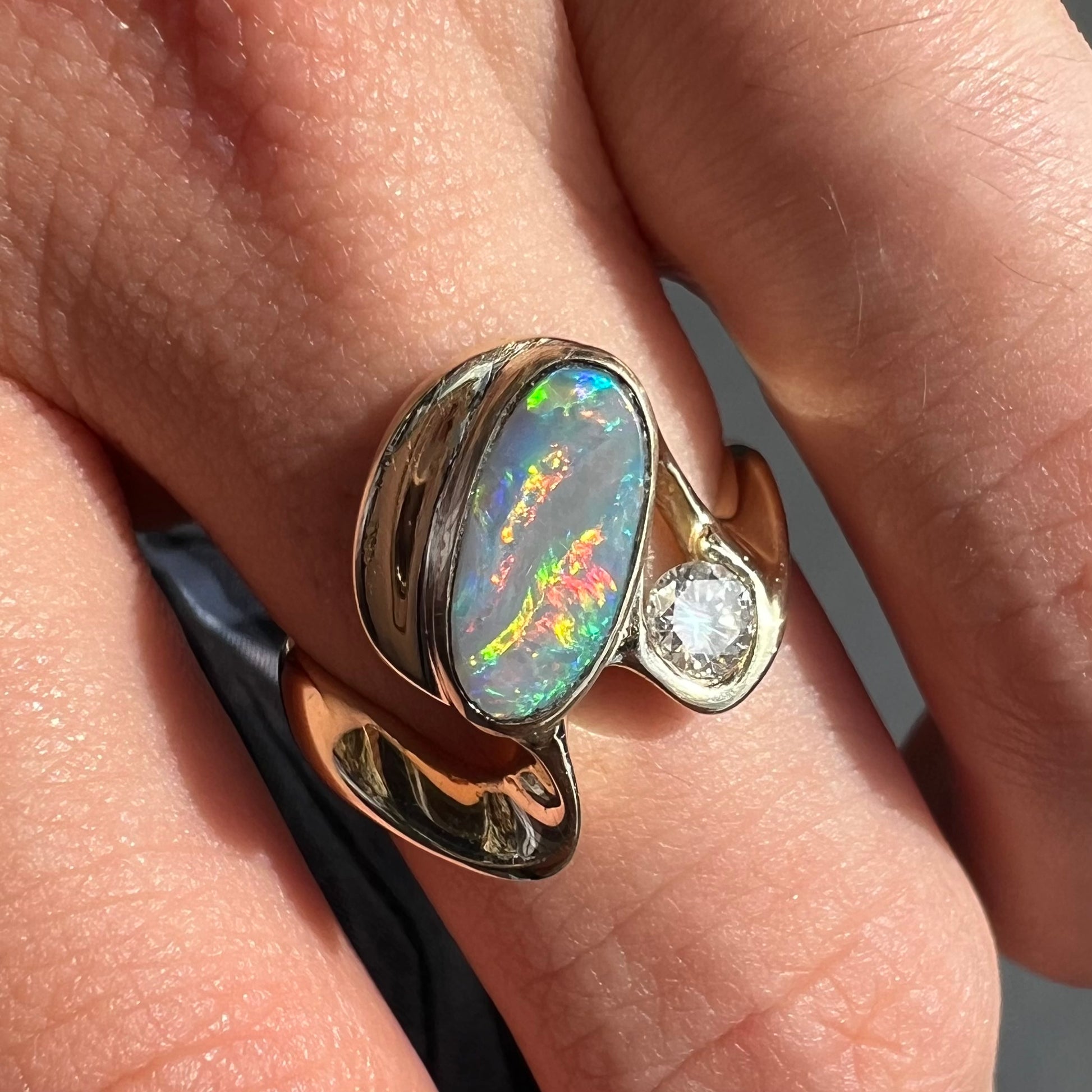 A ladies' yellow gold, bezel set ring mounted with a natural 1.15 carat black opal and round diamond.
